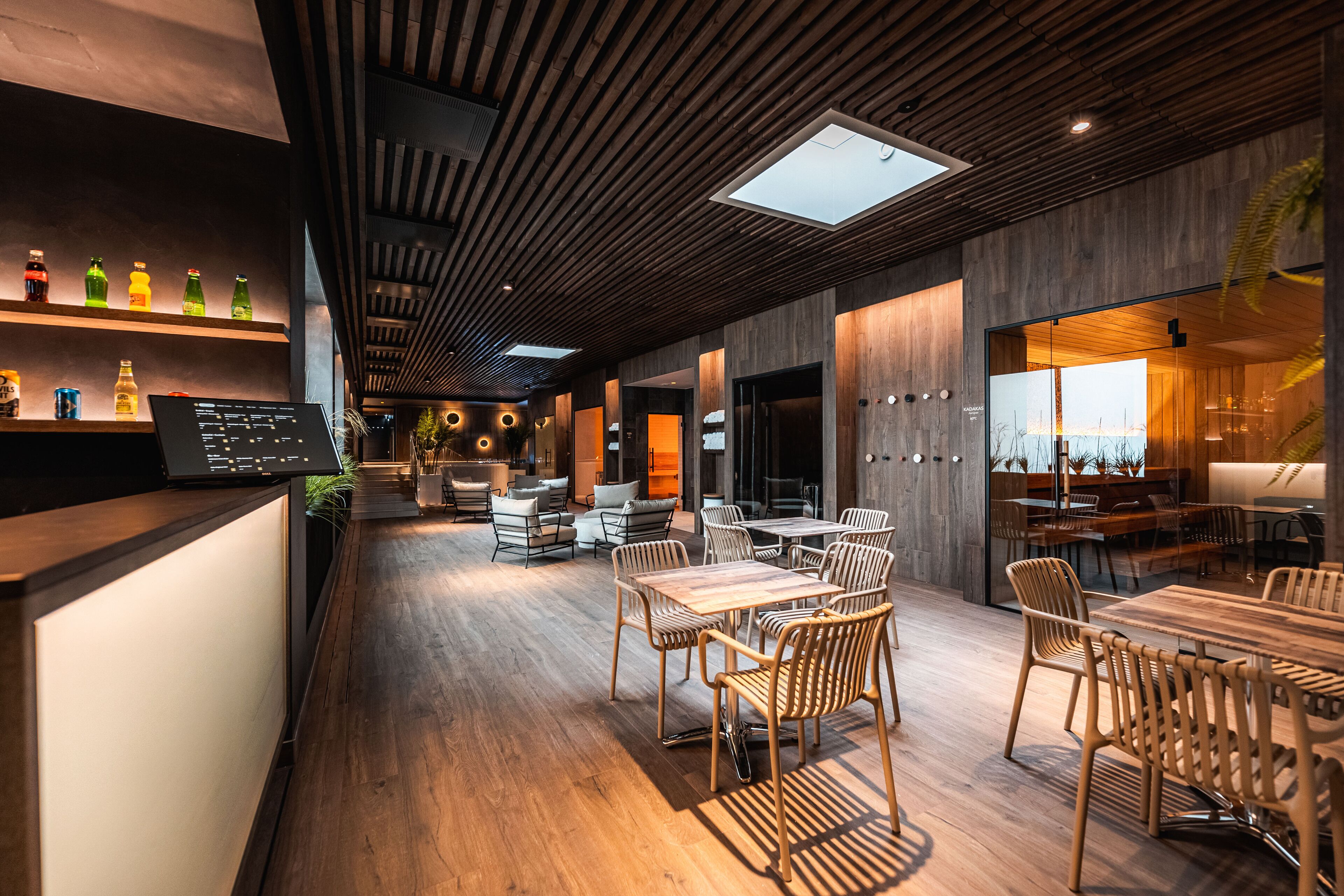 A modern interior with wooden flooring, a reception desk, and a seating area with tables and chairs.
