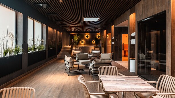 A modern indoor space with wooden flooring, a central seating area with cushioned chairs, and large windows along one wall. - Meri Hotel & SPA (Kuressaare)