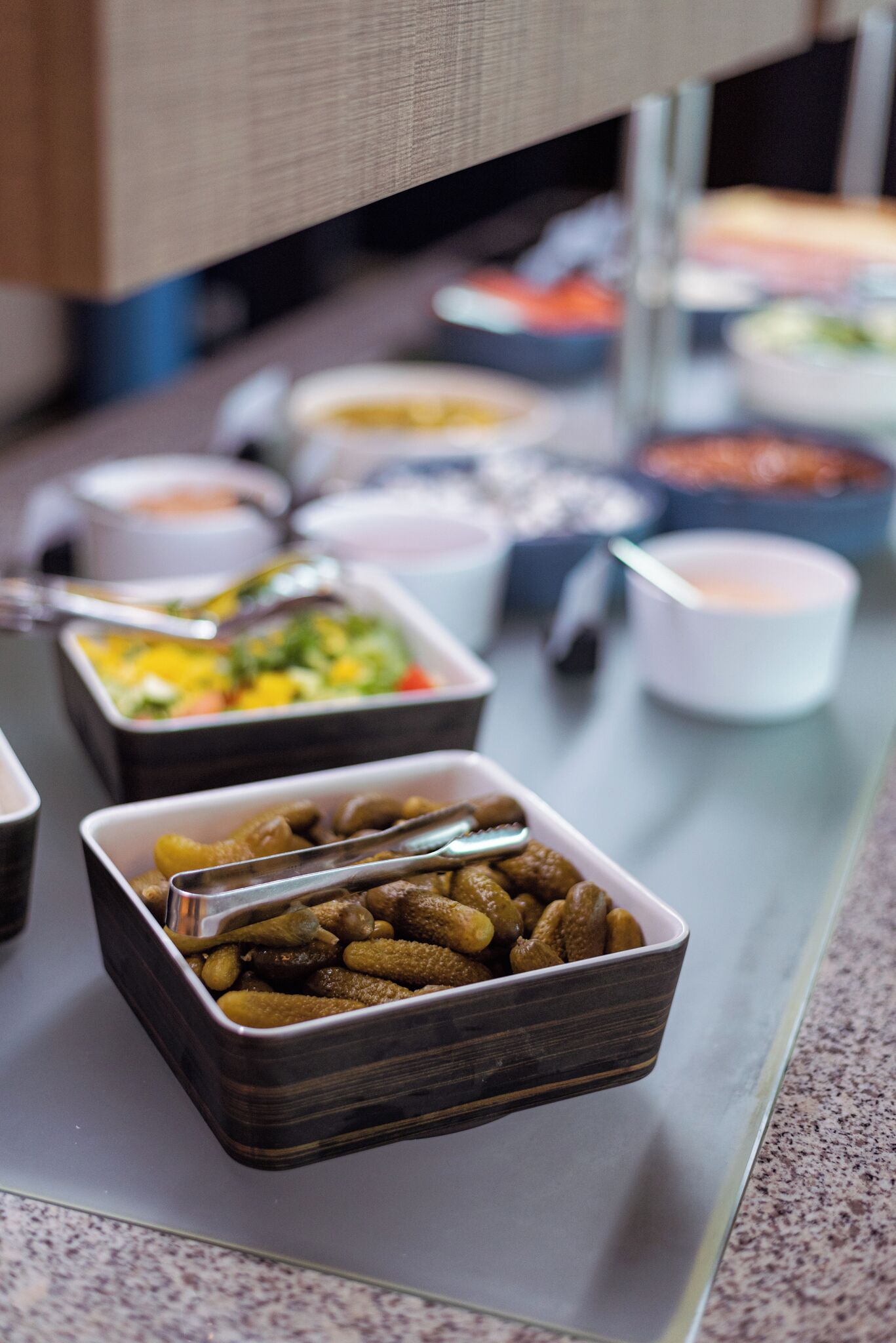 A buffet table with various food containers and utensils.