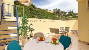 A patio with a table set for two, chairs, a potted plant, and a view of a hillside. - Casa Peggy - Communal pool & garden, just 500m from the beach (Carvoeiro)
