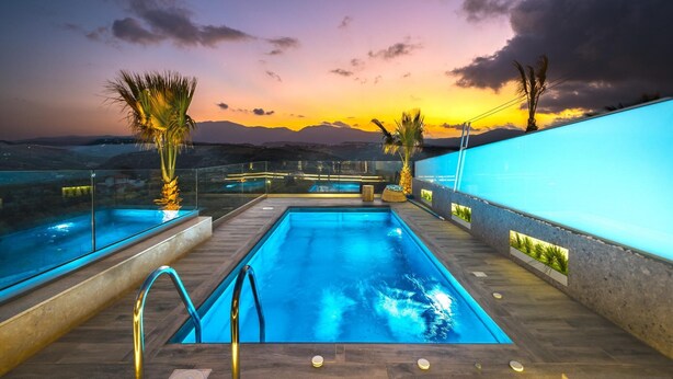A swimming pool with a glass barrier, palm trees, and a sunset view. - Oleas Suite Sun Private Pool (Heraklion)