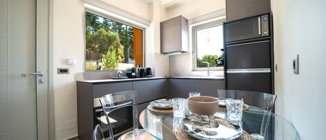A compact kitchen with a glass dining table, built-in appliances, and a view of the outdoors.