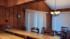 A wooden interior with a long dining table, chairs, and pendant lighting. - Peaceful Cavalier Townhome #2 Near Lake Owen (Cable)