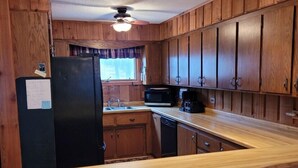 A kitchen with wooden cabinets, a black refrigerator, a microwave, and a wooden countertop. - Peaceful Cavalier Townhome #2 Near Lake Owen (Cable)