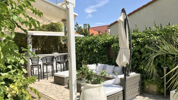 Una zona patio con mobili da esterno, un vaso grande e una pergola.