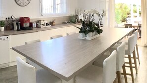 Una cucina moderna con isola centrale, mobili bianchi e un orologio grande appeso al muro.
