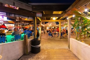 Enjoy dining under the shelter of this covered outdoor space, featuring comfortable seating and tables for a relaxed meal.