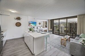 A modern apartment with a kitchen island, a dining area, and a living room with a large window offering a city view.