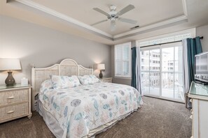 Classic bedroom with a large bed, nightstand, and dresser, offering a view of the outside.