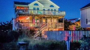 A multi-story house with a balcony, a flag, and a staircase. - The Pup Deck - Duck, Carolina Dunes, 420 Yds to Beach, Pool, Hot Tub, Pets OK, Flex Stays (Duck)