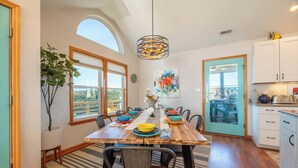 A dining area with a wooden table, chairs, and a hanging light fixture. - The Pup Deck - Duck, Carolina Dunes, 420 Yds to Beach, Pool, Hot Tub, Pets OK, Flex Stays (Duck)