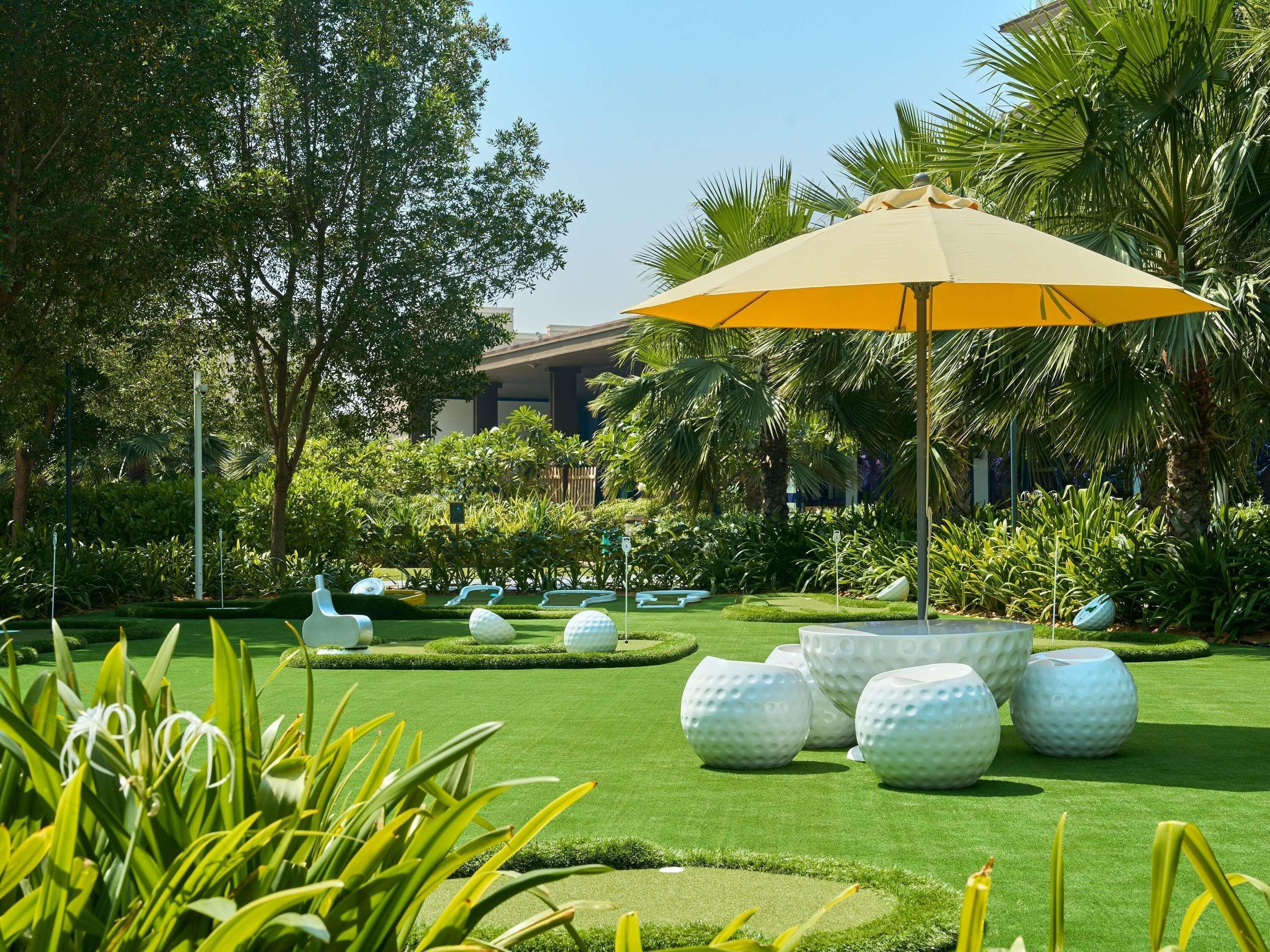 Un jardin bien entretenu, agrémenté d’une sculpture en forme de balle de golf, d’un parasol jaune et d’une végétation luxuriante.