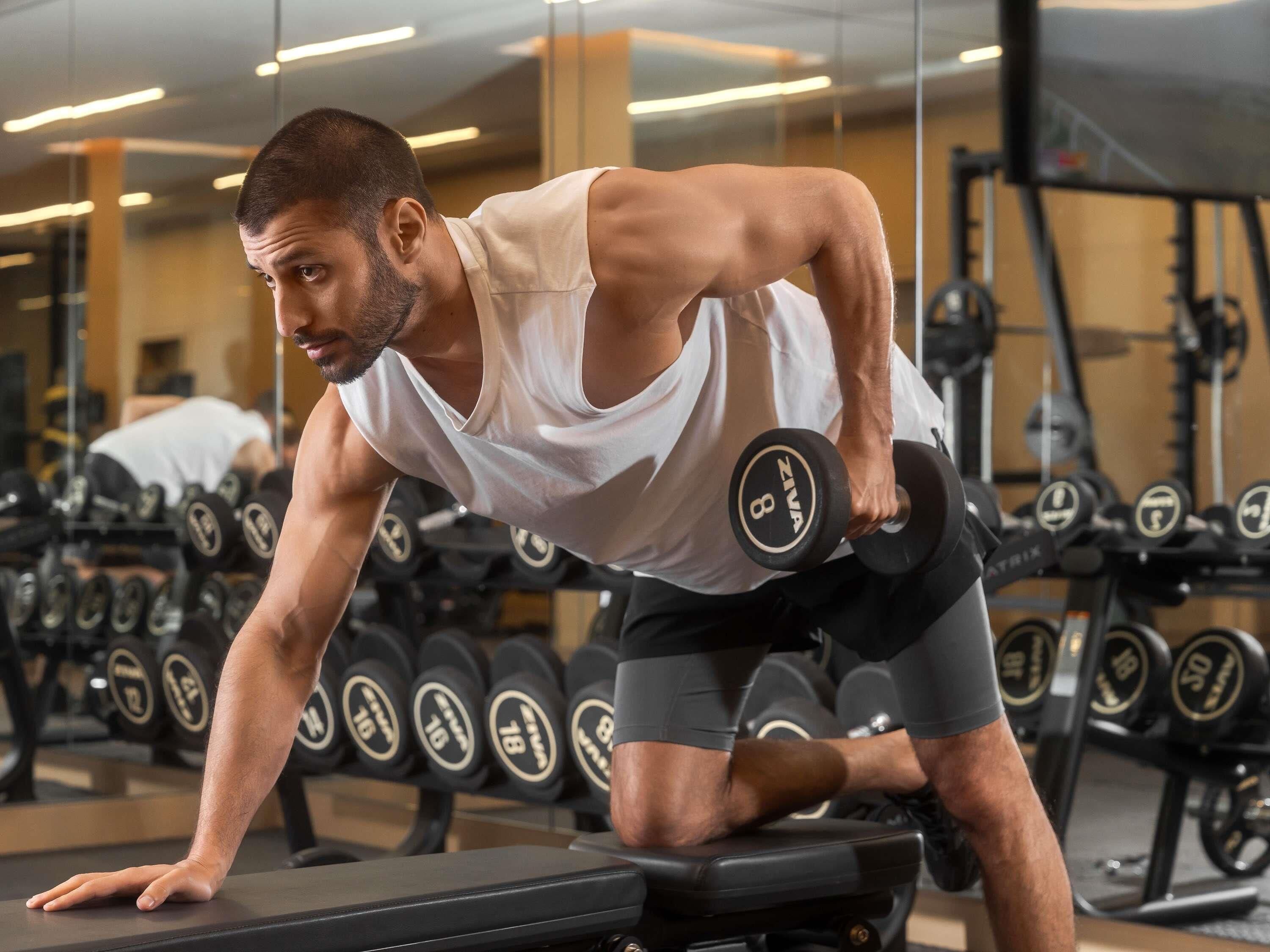 Un gimnàs amb equipament de musculació, incloent-hi peses i panells.