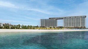 A large hotel with multiple floors and balconies overlooking a beach and the sea. - Mövenpick Resort Al Marjan Island (Ras Al Khaimah)