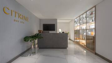A reception area with a modern design, featuring a reception desk, a flat-screen TV, and a glass display case with items.