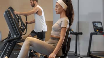 A gym with stationary bikes and treadmills, a man and a woman exercising.