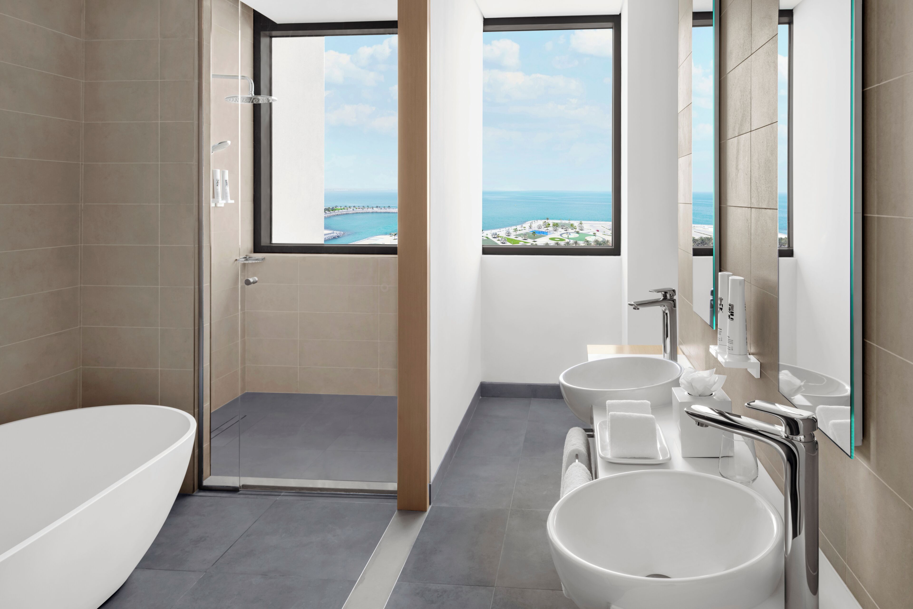 A modern bathroom with a bathtub, two sinks, and a shower.