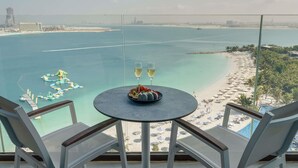 A balcony with a table set for two, overlooking a beach and water. - Mövenpick Resort Al Marjan Island (Ras Al Khaimah)