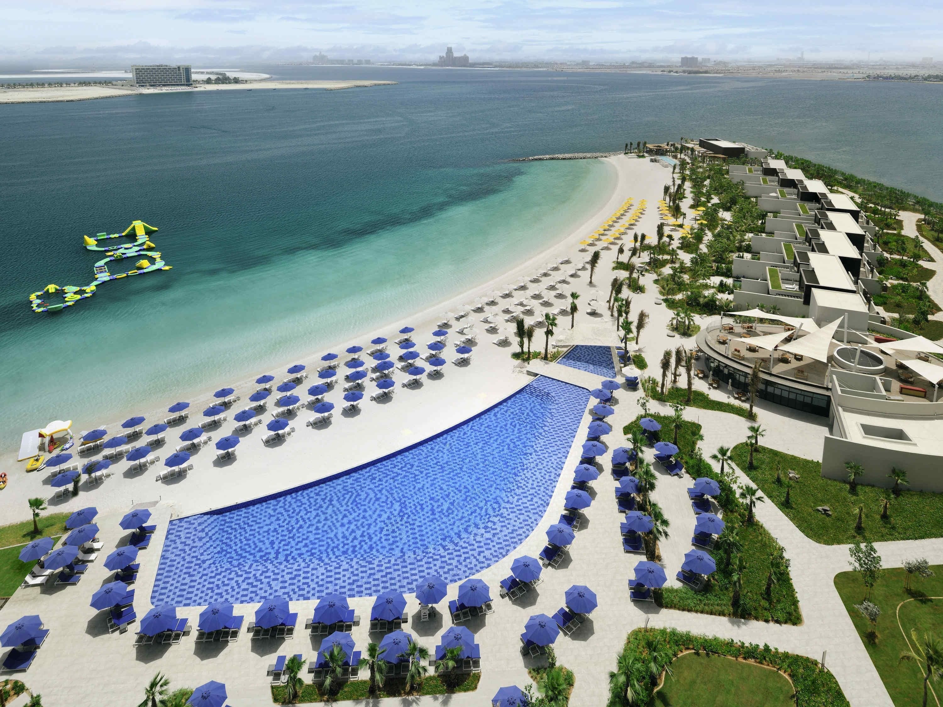A resort with a large pool, beach area, and ocean view.