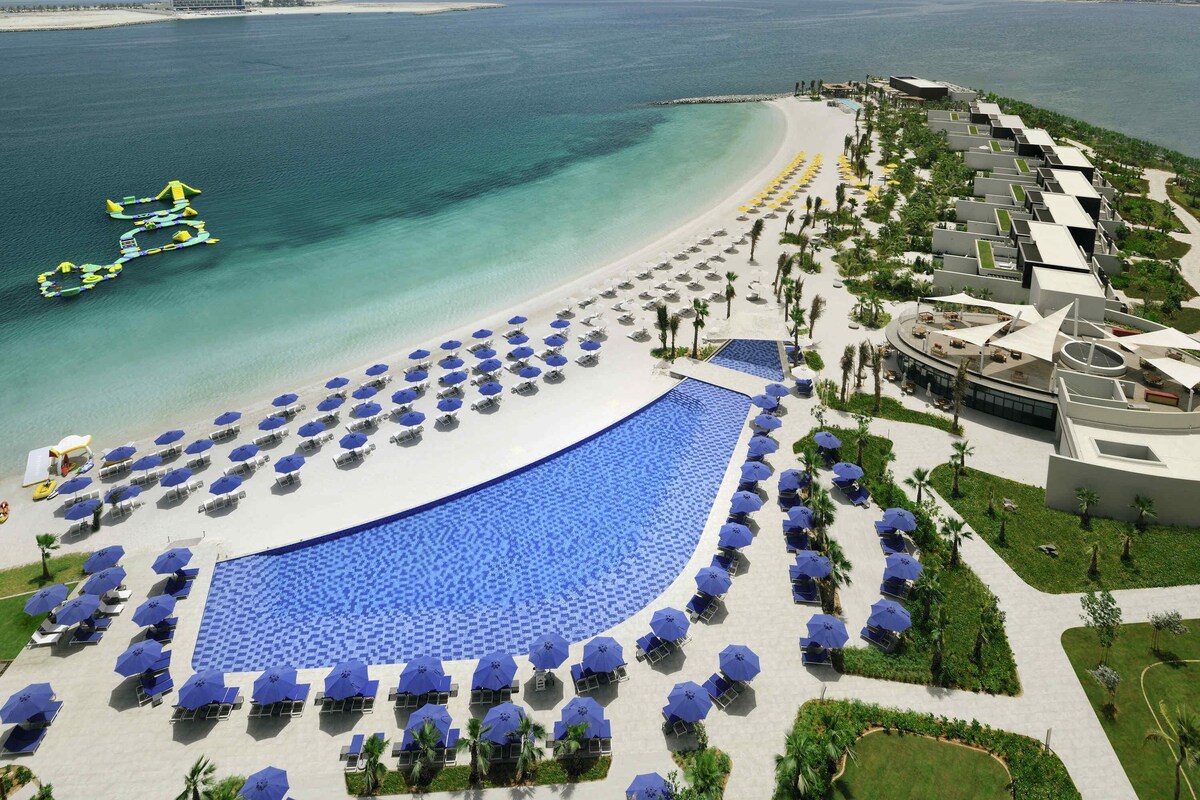 Een resort met een groot zwembad, een strandgedeelte en uitzicht op de oceaan.