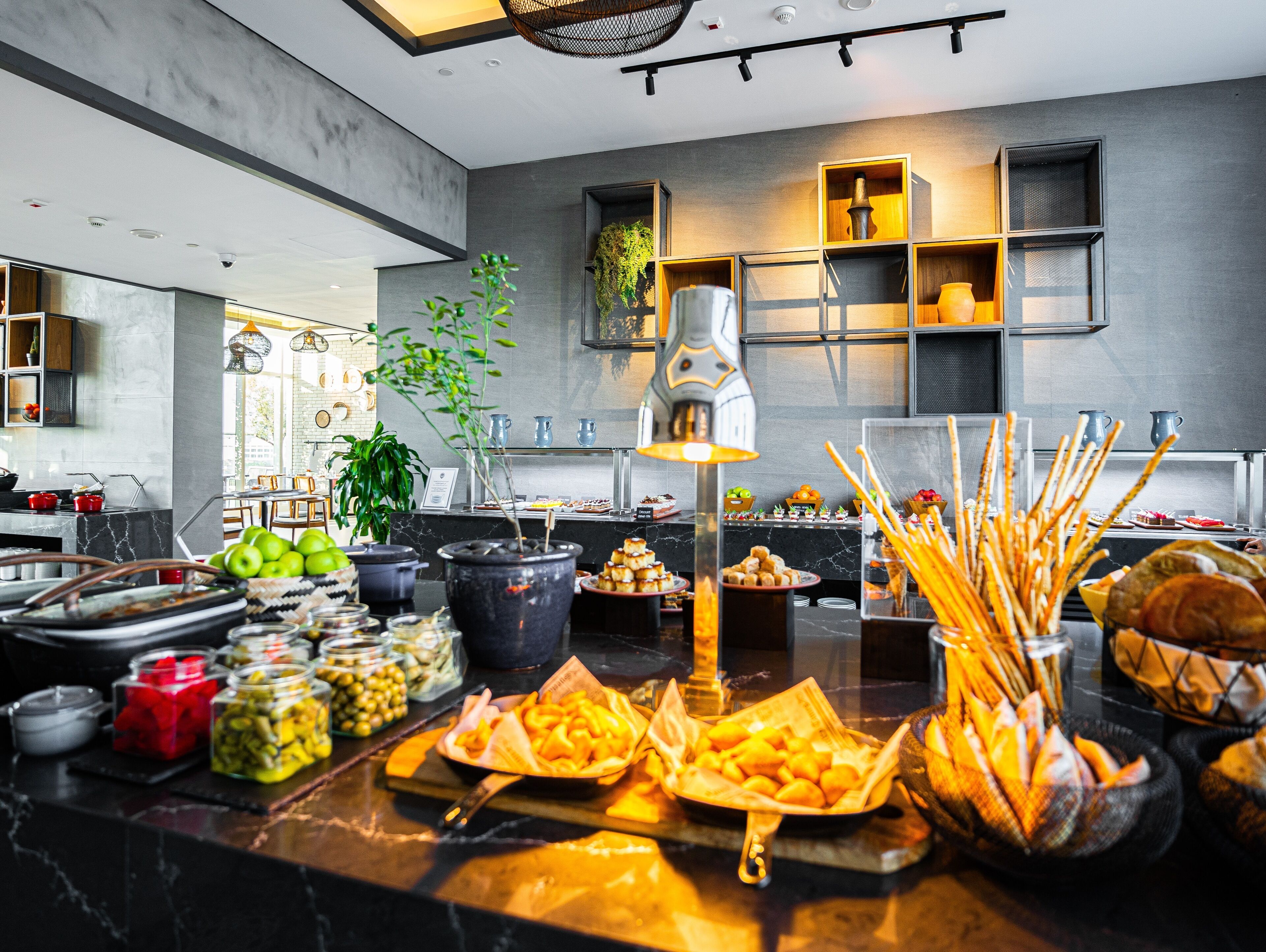 A buffet setup with various food items and a potted plant.