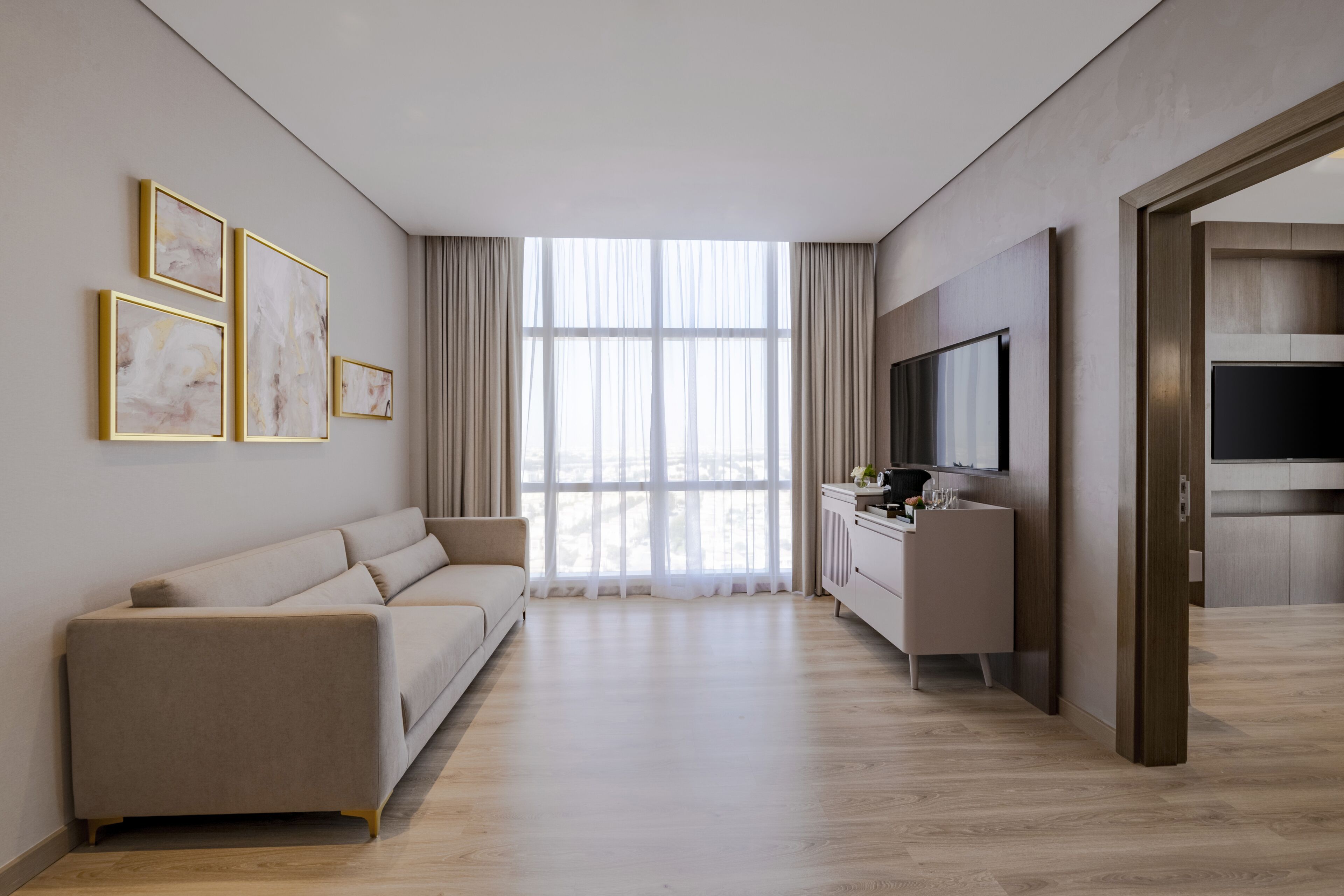 A modern living room with a sofa, a TV, and artwork on the wall.