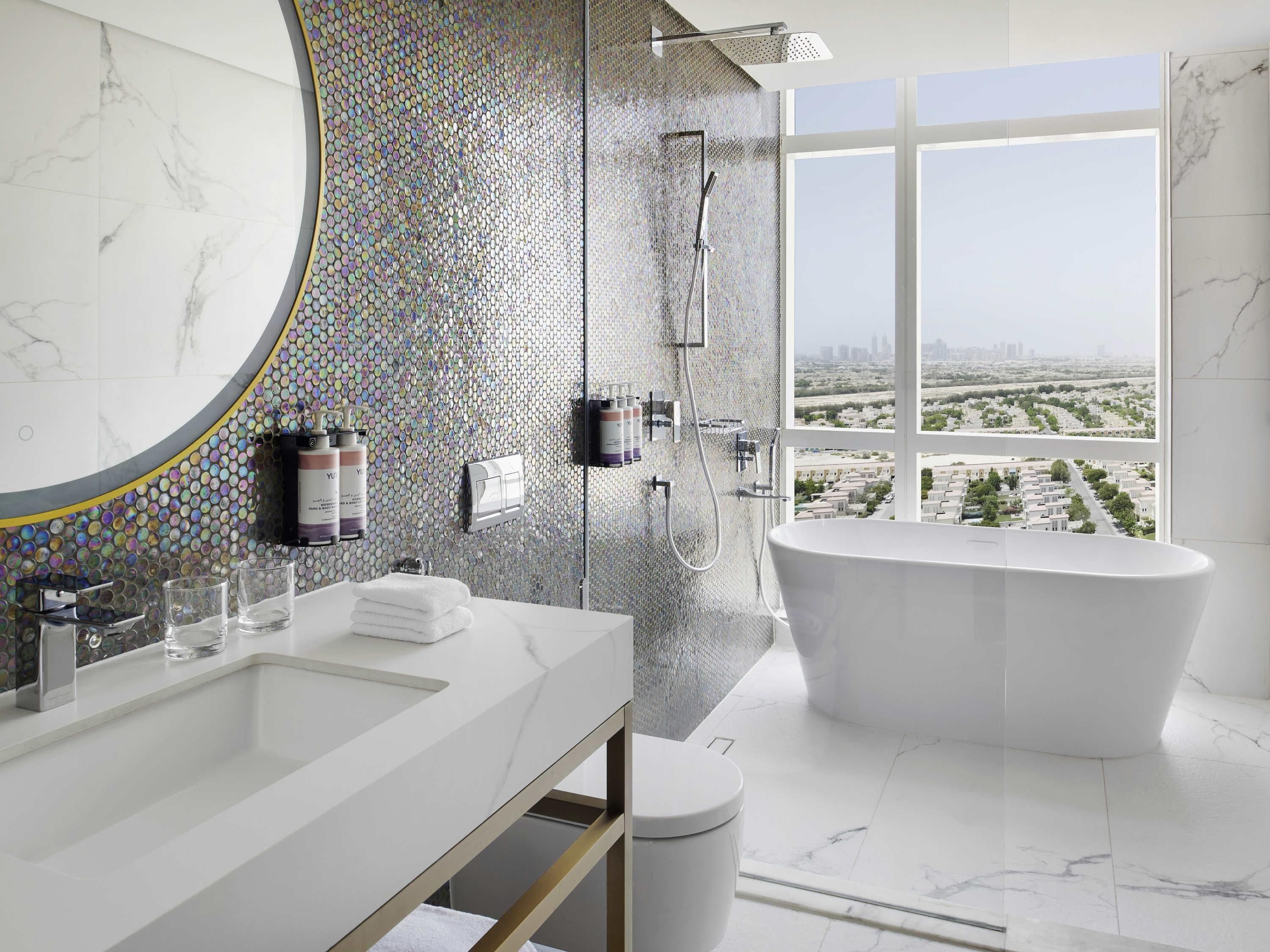 A modern bathroom with a large bathtub, a shower, and a vanity with a mirror.