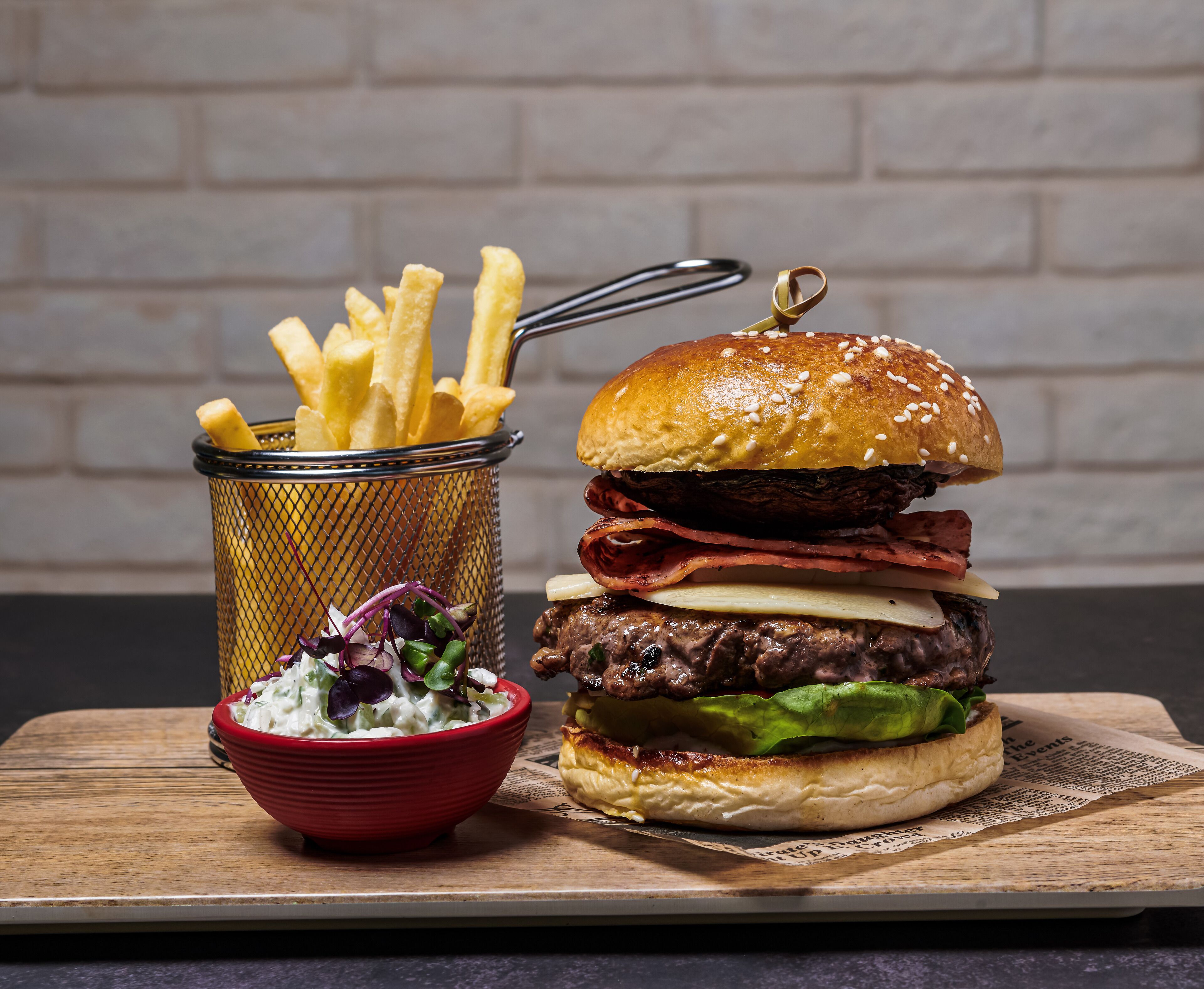 Een hamburger met friet en een salade op een houten plank.