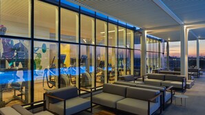 Un espace piscine intérieur moderne, doté de murs en verre, de sièges et d’équipements d’exercice.