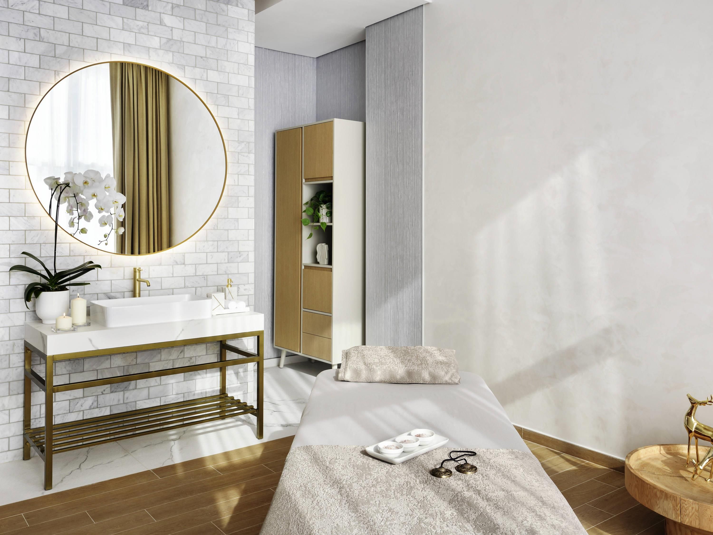 A modern bathroom with a white sink, gold fixtures, and a large mirror.