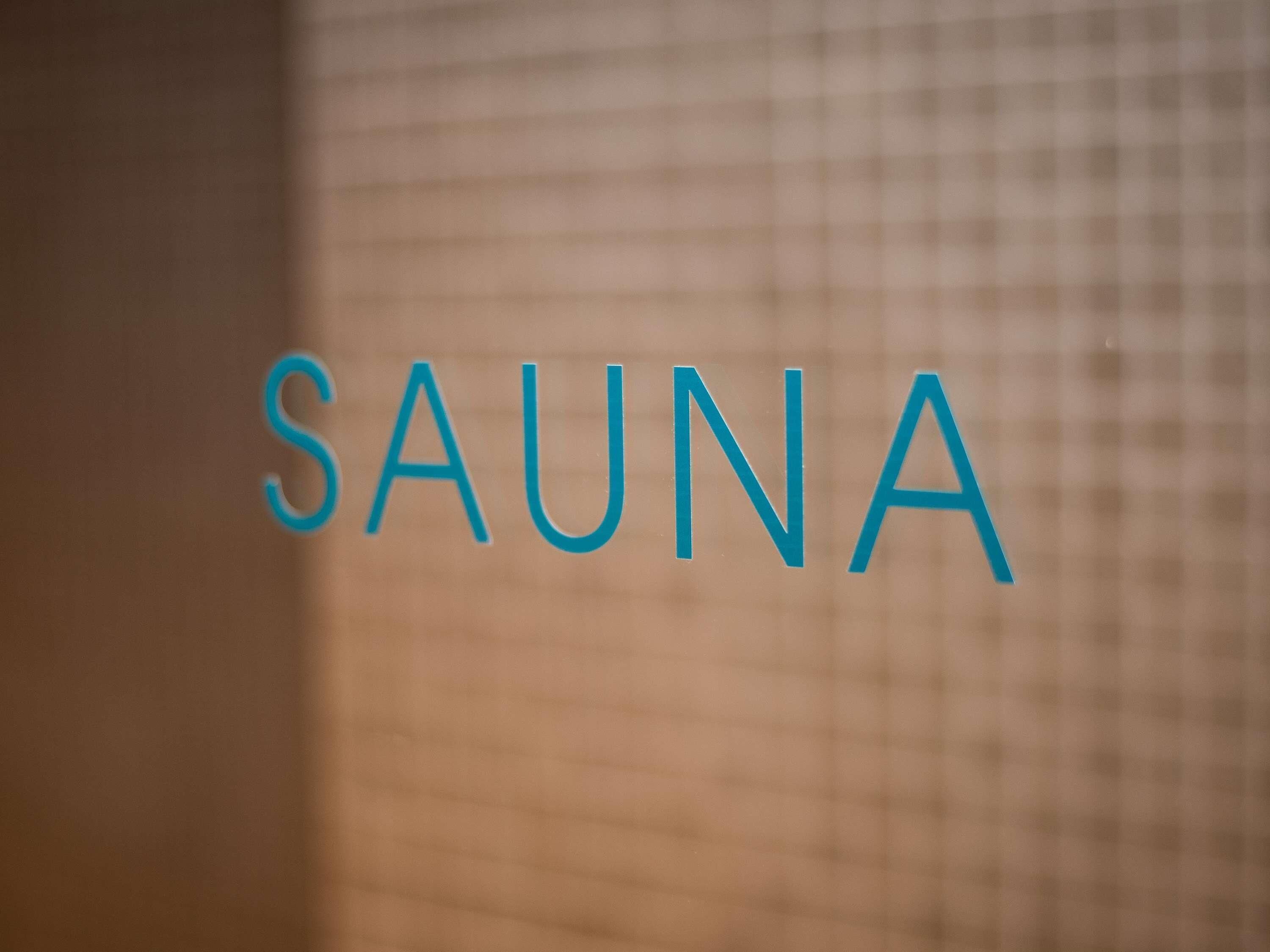 The word "SAUNA" in blue letters on a textured wall.