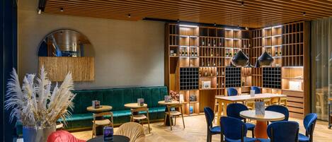 A modern lounge area with a green sofa, round tables, and blue chairs.