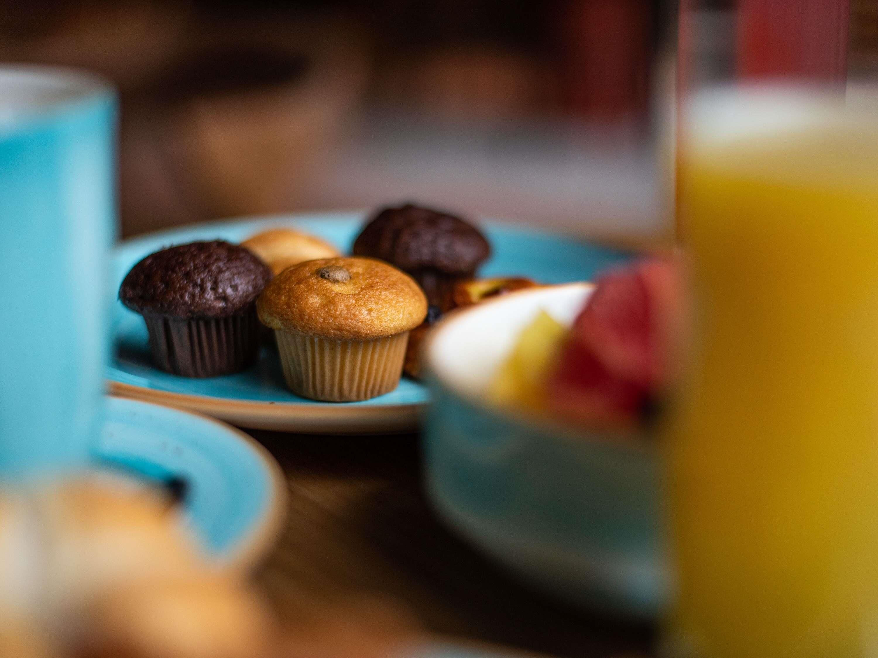 Una mesa con un plato de muffins y un bol de fruta.
