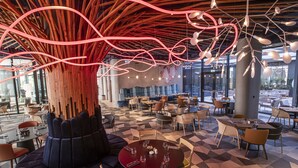 A modern restaurant with a unique ceiling design, multiple seating areas, and a view of the outdoors.