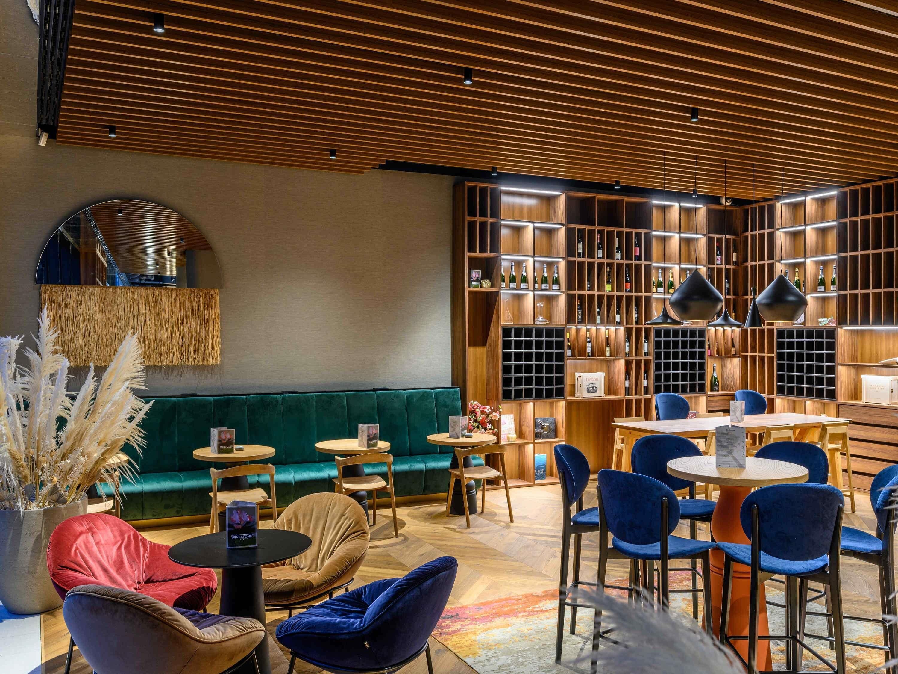 Un intérieur moderne avec un canapé vert, des tables rondes et des chaises bleues.