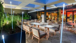 An outdoor seating area with modern furniture and a view of the restaurant interior.