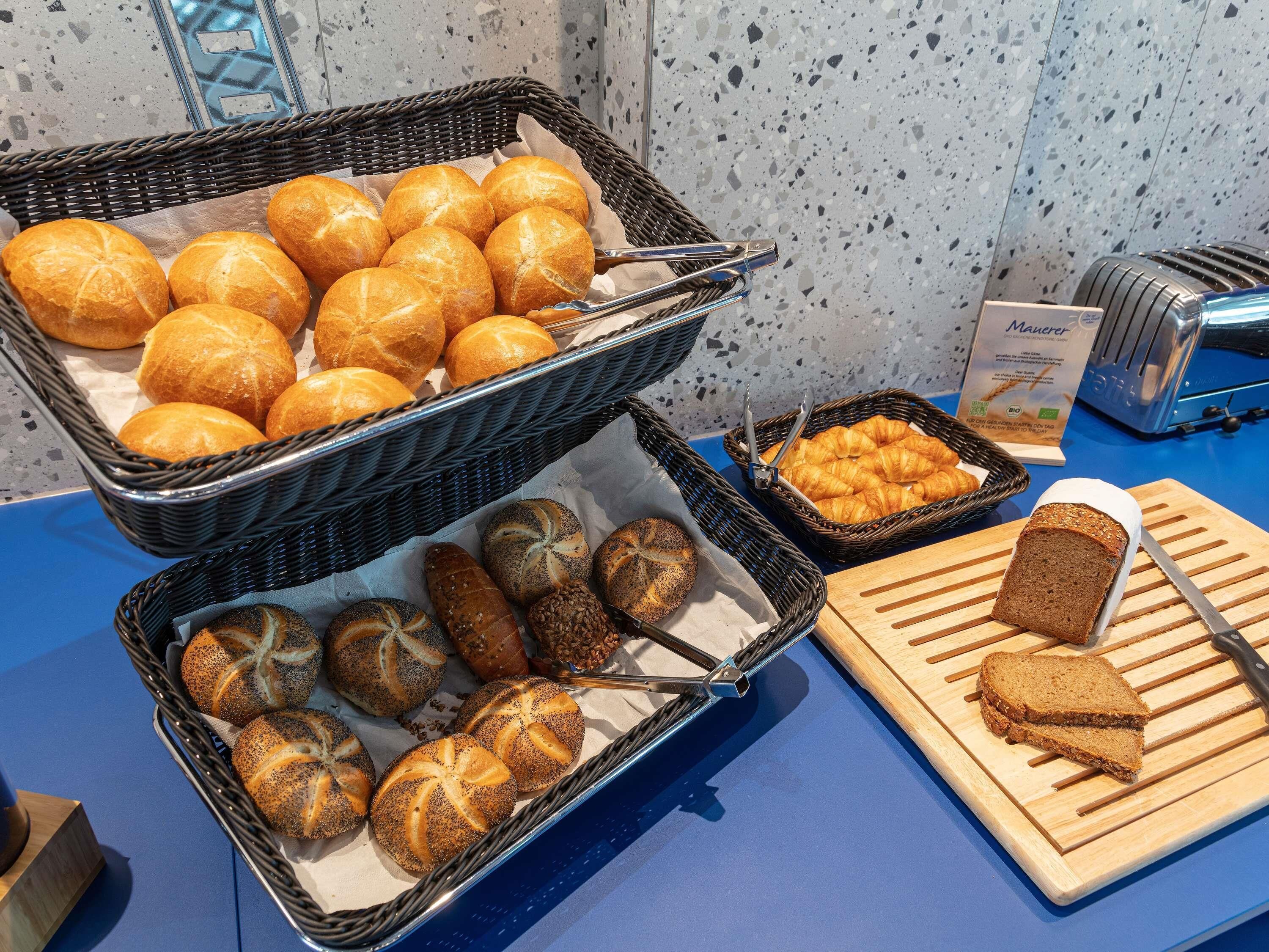 A buffet with various breads and pastries, a toaster, and a cutting board with bread slices.