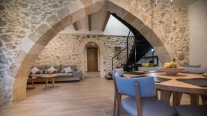 Ein Interieur mit Steinwänden, einer Couch, einem Esstisch und Stühlen.