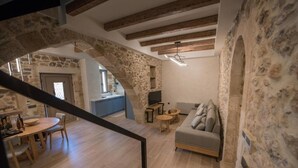 Ein rustikales Interieur mit freiliegenden Steinen, einem Holzespeisetisch und einer Couch in einem gemütlichen Wohnbereich.