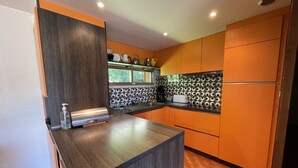 A modern kitchen with dark wood cabinets, a central island, and a patterned backsplash. - Chalet les Digitales - Rocher du cerf (Le Lioran)