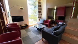 A modern living room with a sofa, armchairs, a coffee table, and a TV. - Chalet les Digitales - Rocher du cerf (Le Lioran)