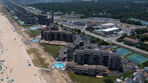 Vista aérea de un hotel costero con varios edificios altos, una playa y un estacionamiento.