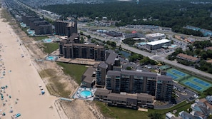 Vista aérea de un hotel costero con varios edificios altos, una playa y un estacionamiento.