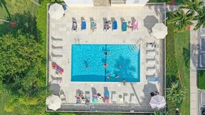 An aerial view of a swimming pool area with lounge chairs and umbrellas.