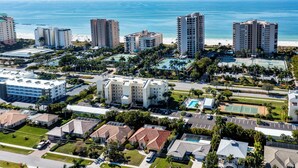 A coastal hotel complex with multiple high-rise buildings, a beach, and a tennis court.
