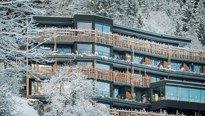 Un hotel de varios pisos con balcones, rodeado de árboles cubiertos de nieve.