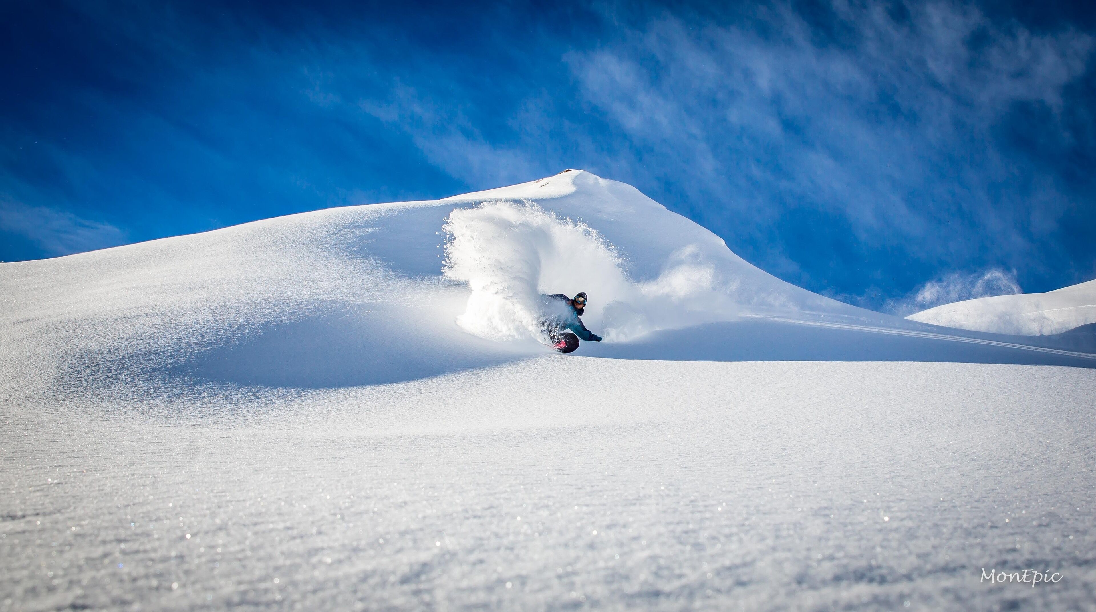 A snowboarder carving through a snow-covered slope.