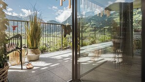 Un balcón con vistas a montañas, una planta en maceta y una silla de mimbre.