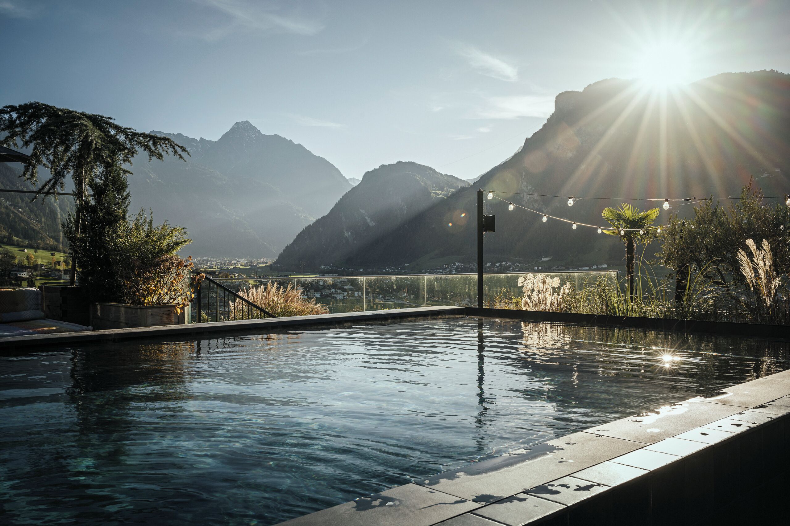 Piscina con vista a la montaña, rodeada de plantas y un cielo despejado.