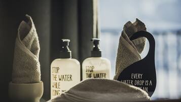 Une salle de bain équipée de serviettes, d’un distributeur de savon et d’une affiche sur la nécessité d’économiser l’eau.